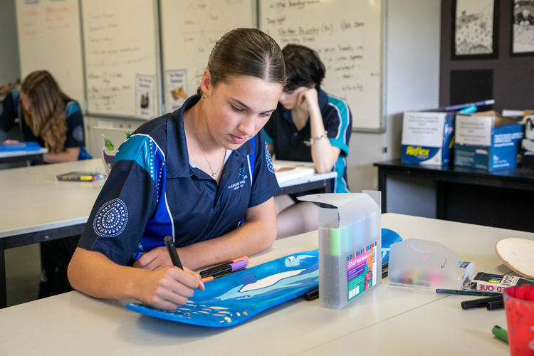 Girl drawing a colourful design on a skateboard