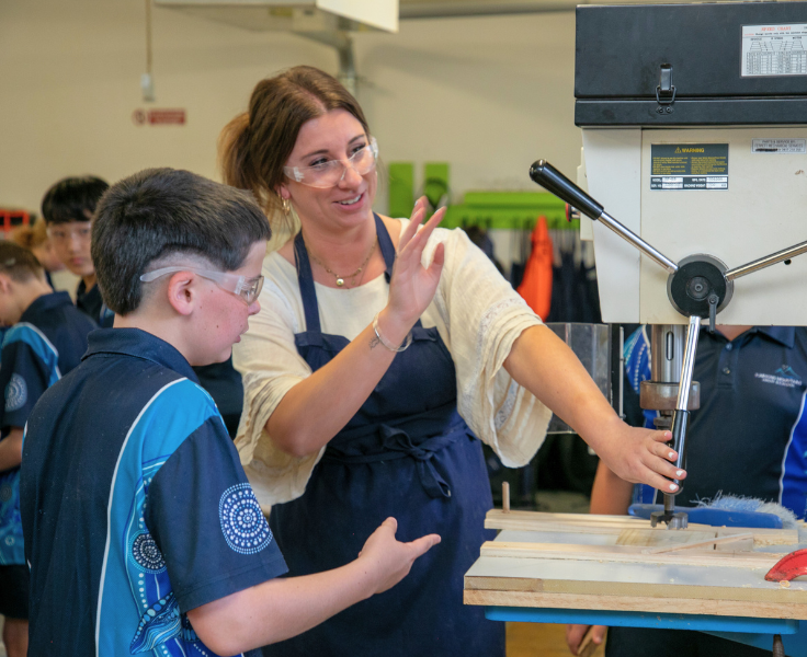 Teacher showing boy in TAS how to operate drill