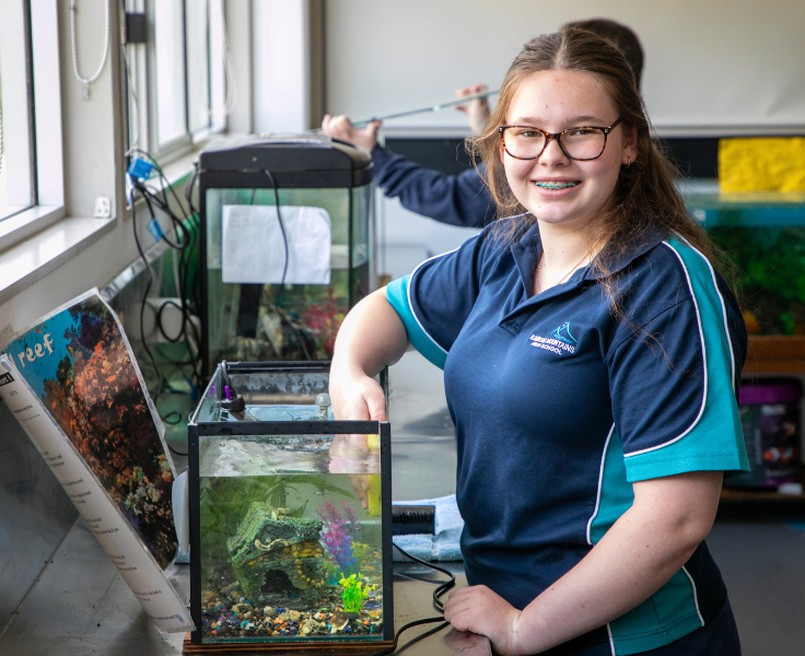Smiling girl with hand in fish tank