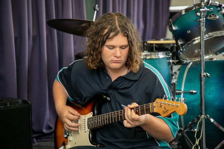 Boy in school uniform plays the guitar