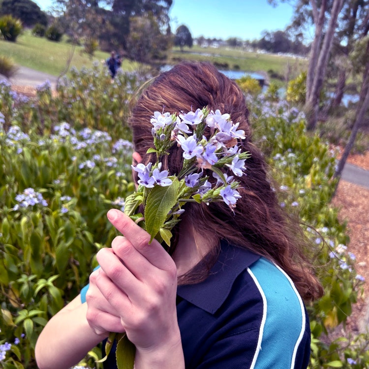 Student in the gardens holding a bunch of flowers